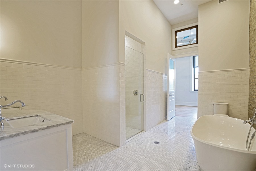 a white bathroom with a tub and a shower and a sink