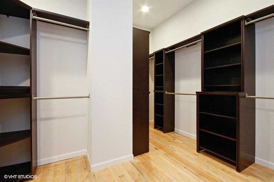 a large walk in closet with white walls and wood floors