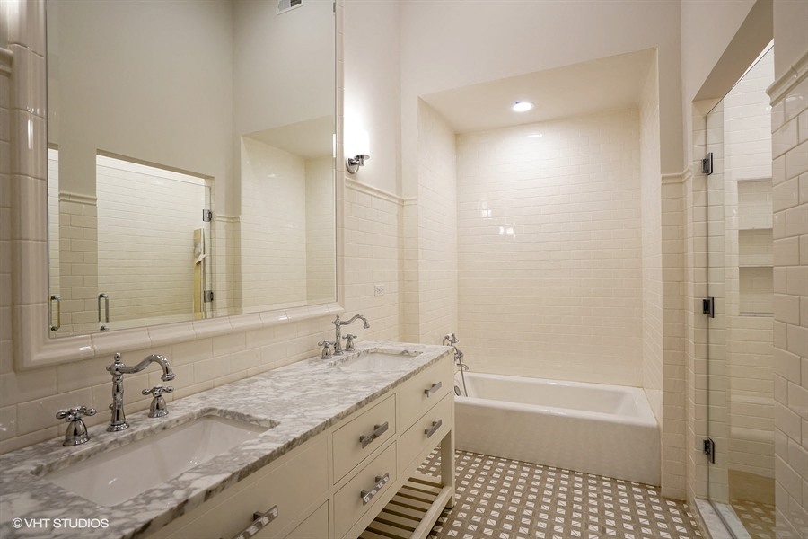 a bathroom with two sinks and a tub and a mirror