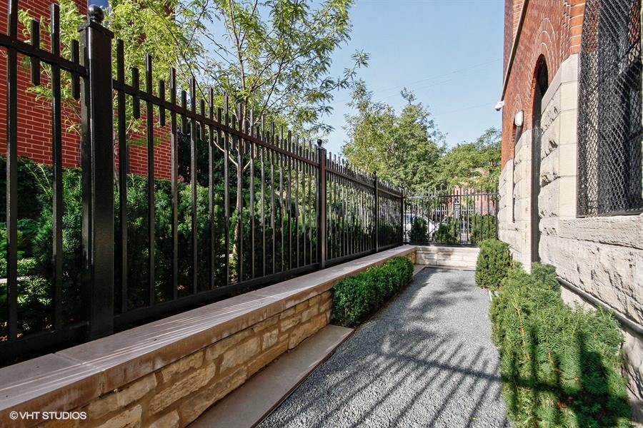 a walkway next to a black fence and a brick building