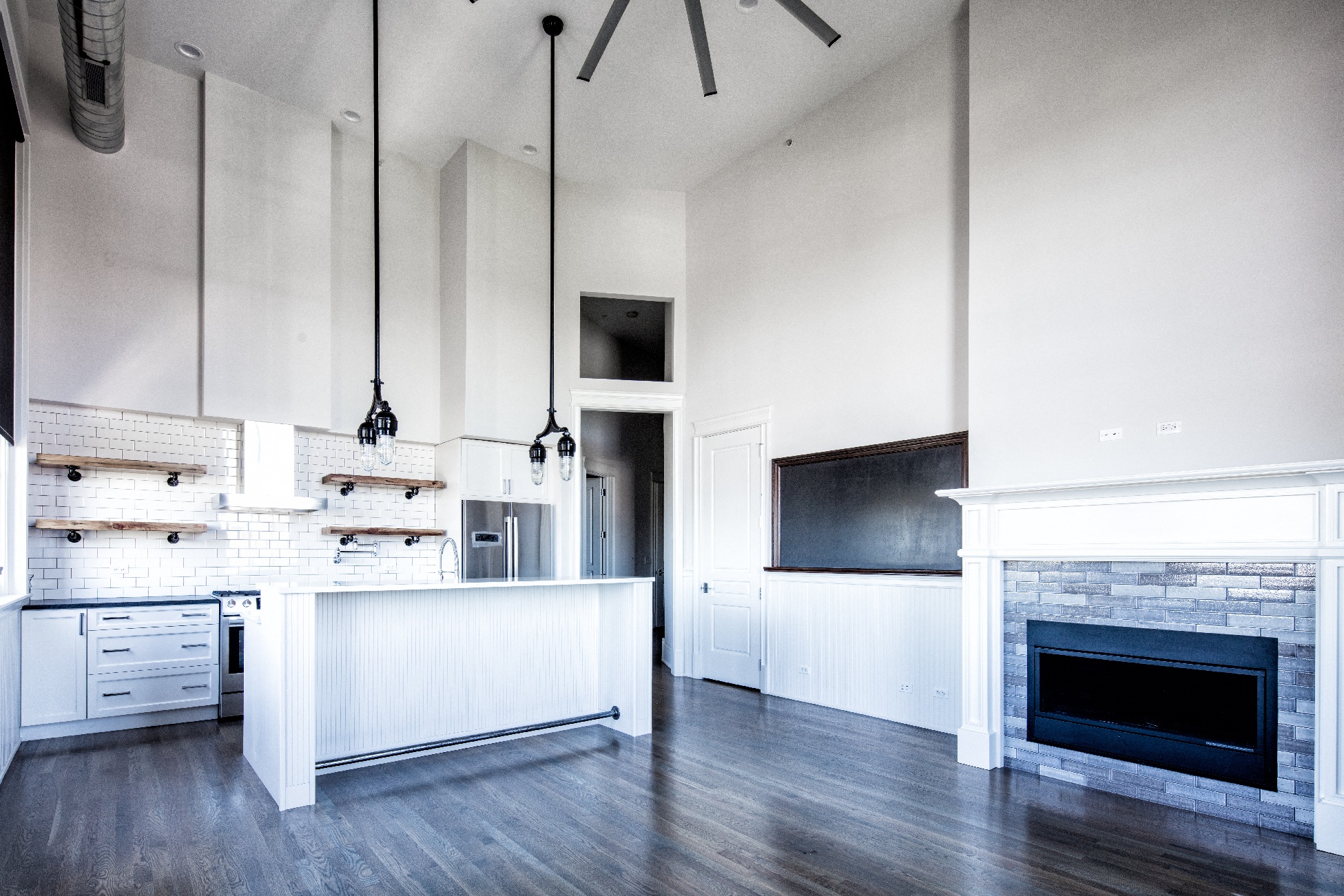 a large white kitchen with a fireplace and a large island