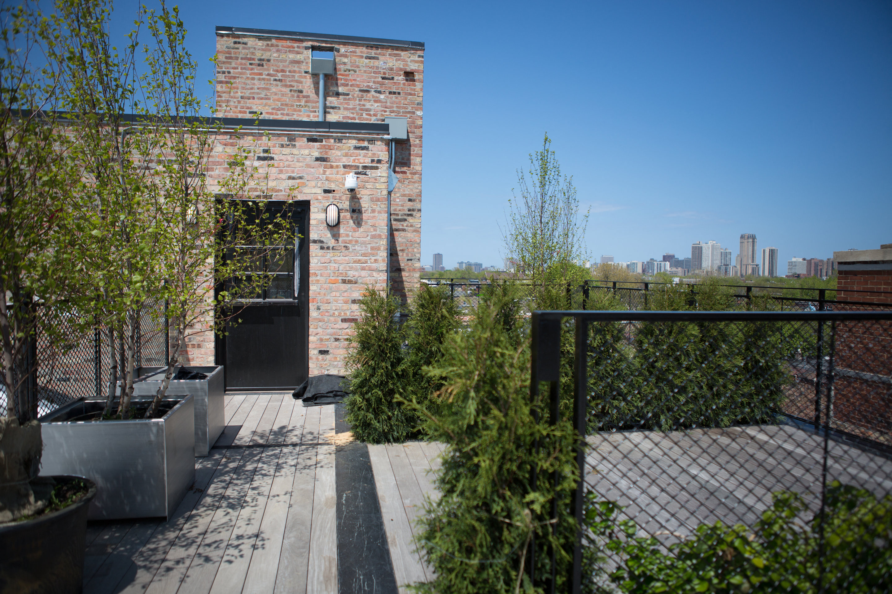 the roof terrace has a view of the city skyline and a brick building with
