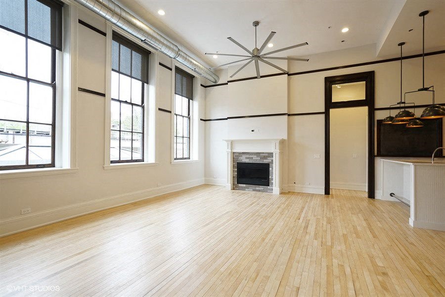 an empty living room with a fireplace and wooden floors