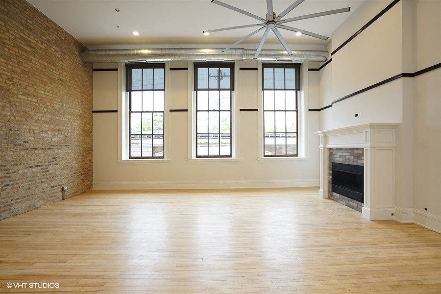 an empty living room with a fireplace and windows