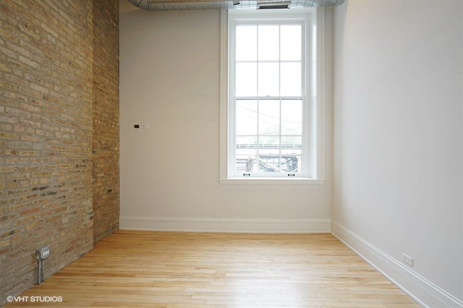 an empty room with a window and a wooden floor