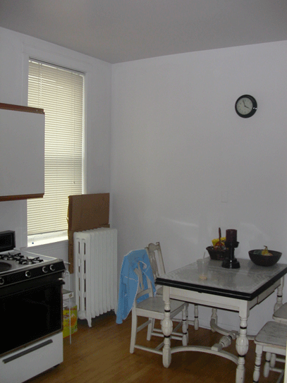 a kitchen with a table and a stove and a clock on the wall