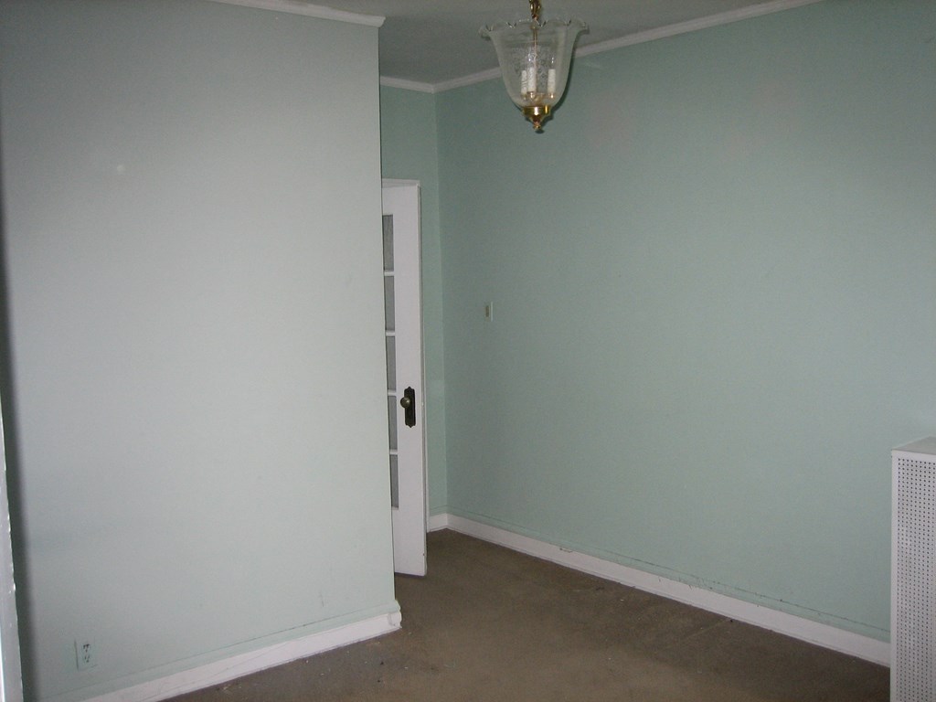 a room with green walls and a white door and a lantern on the ceiling