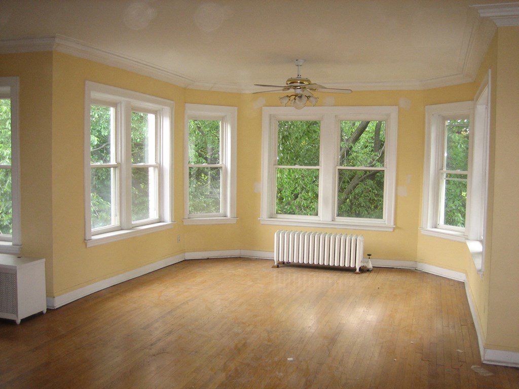 an empty living room with yellow walls and a wood floor