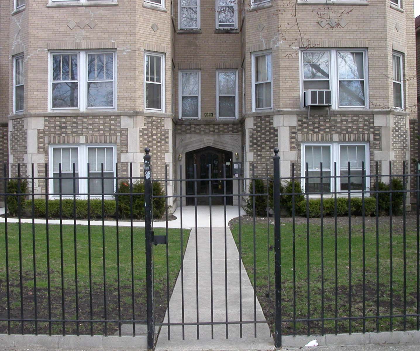 the front of a brick house with a wrought iron gate