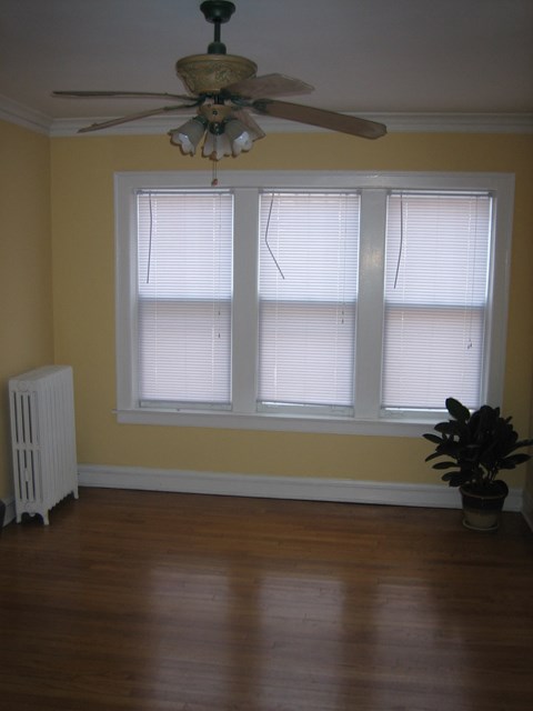 a living room with a ceiling fan and three windows