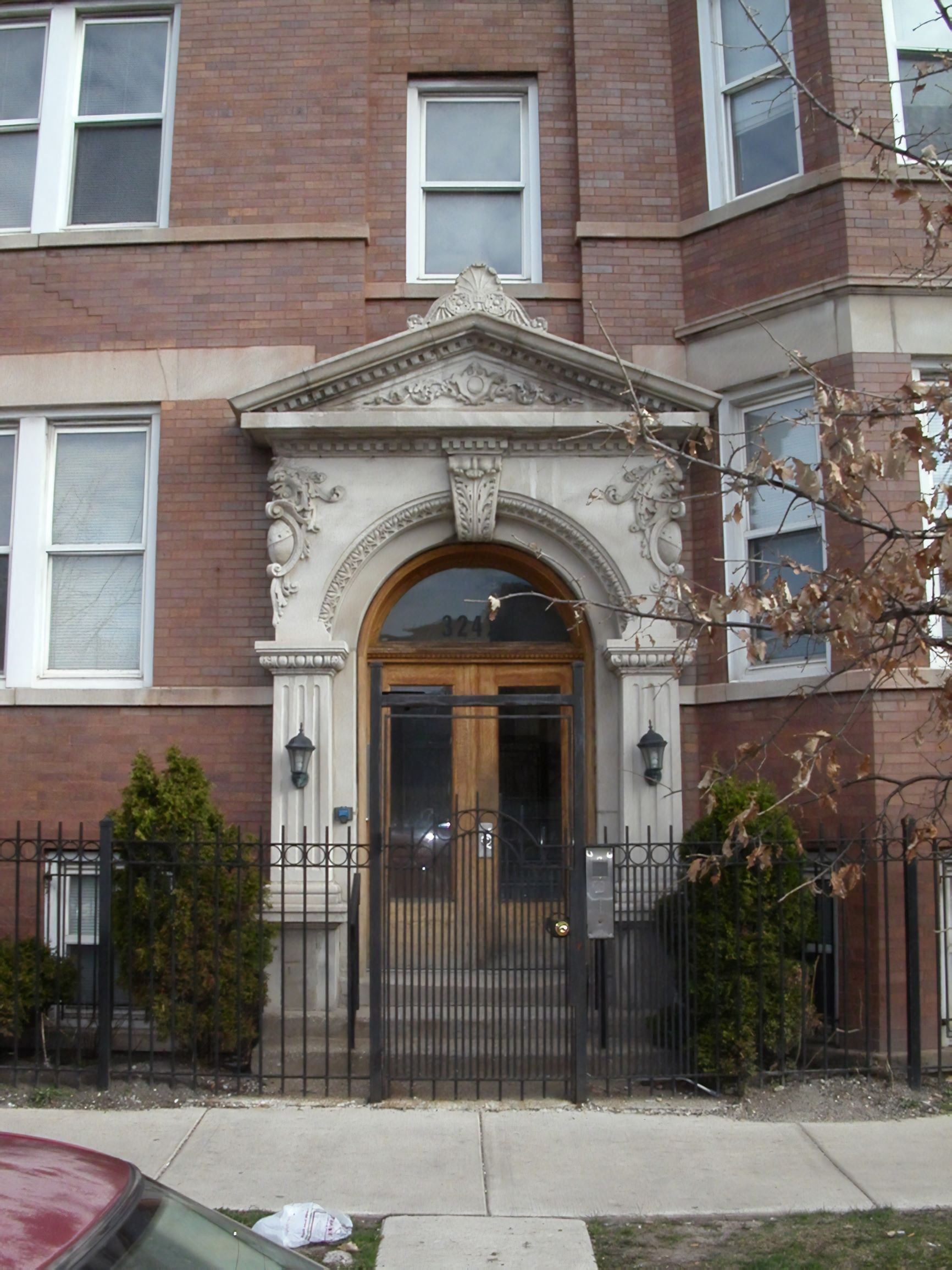 the front door of a brick building with a wrought iron gate