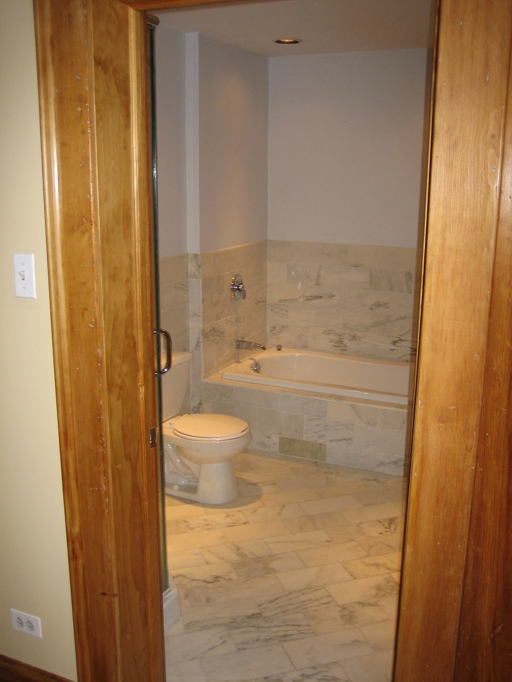 the door is open to a bathroom with a toilet and a tub