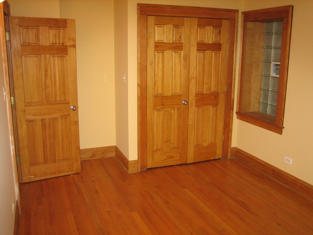 a living room with wooden floors and two wooden doors