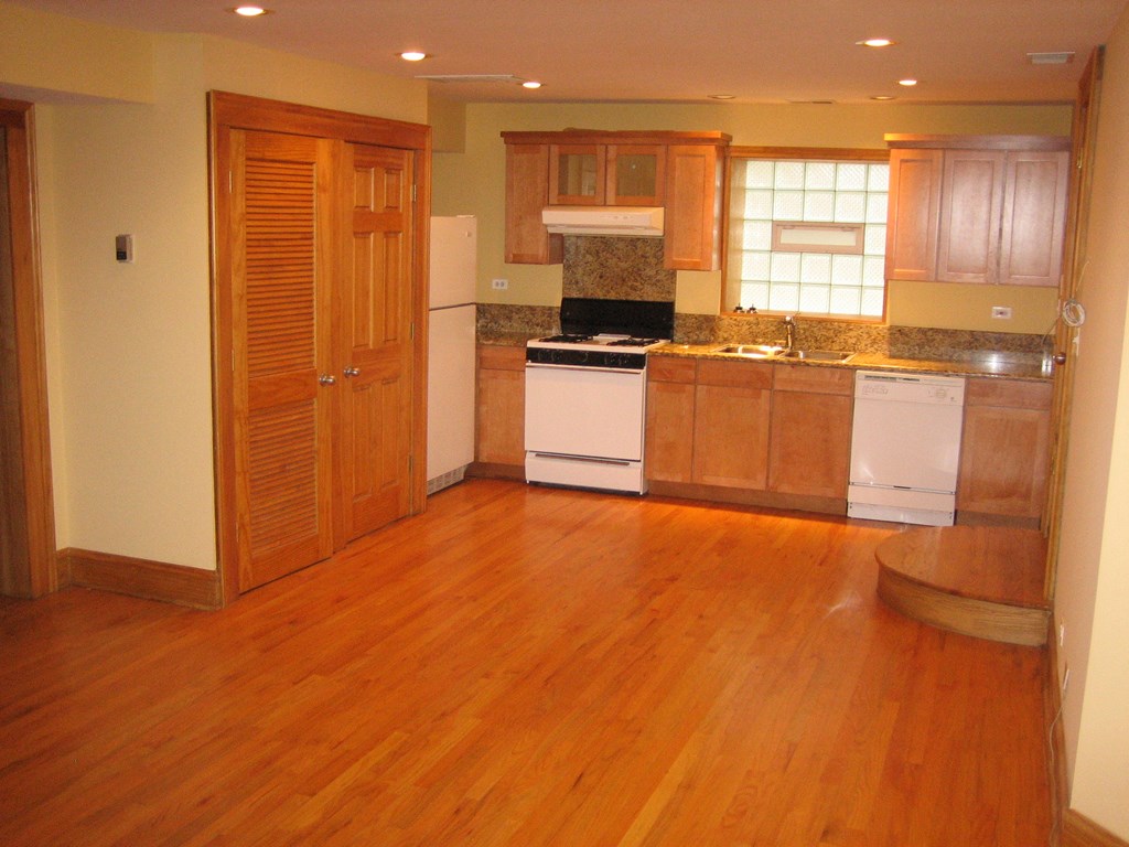 an empty kitchen with wooden floors and white appliances