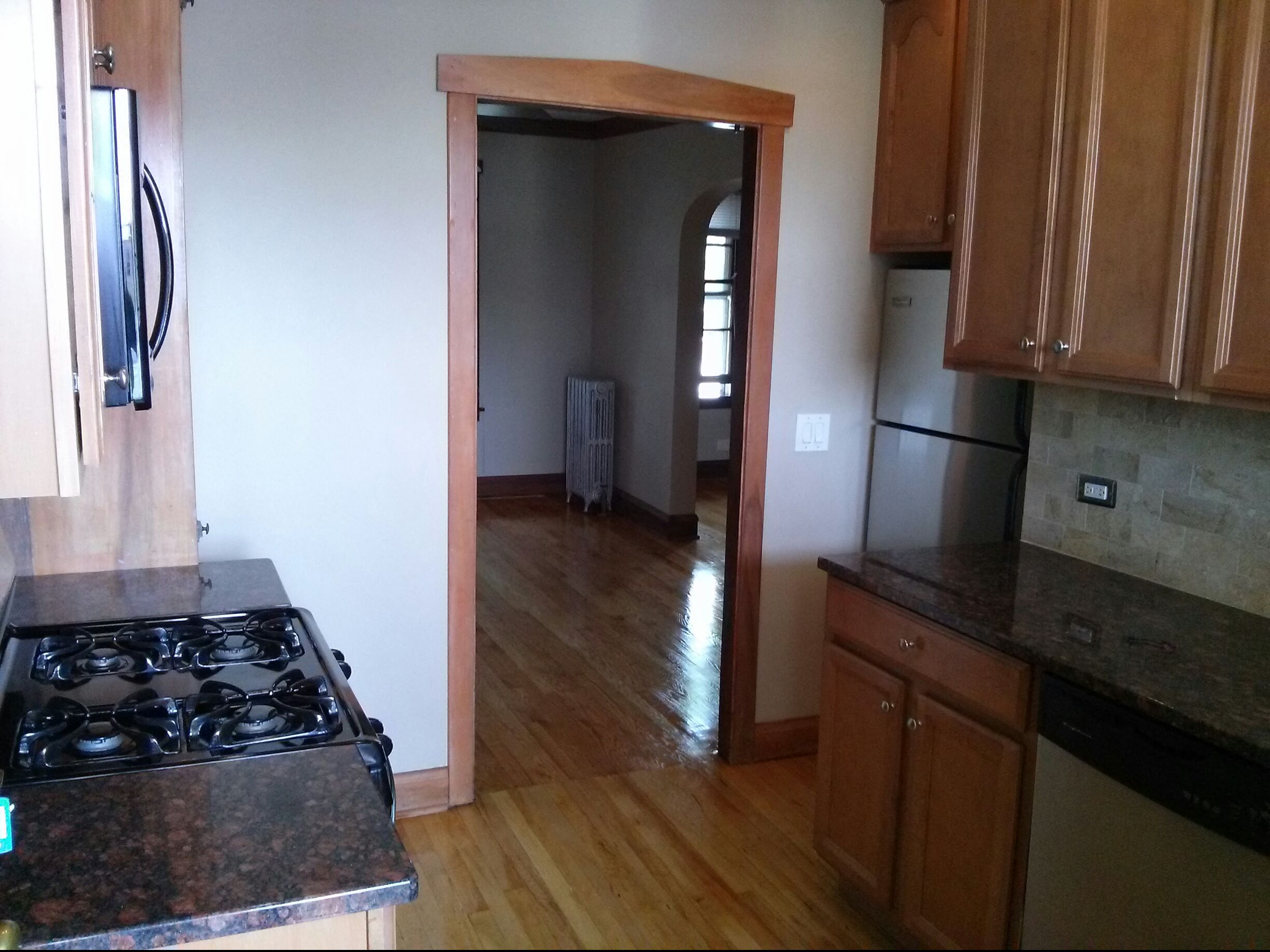 the kitchen and living room of a house with wood flooring and a stove