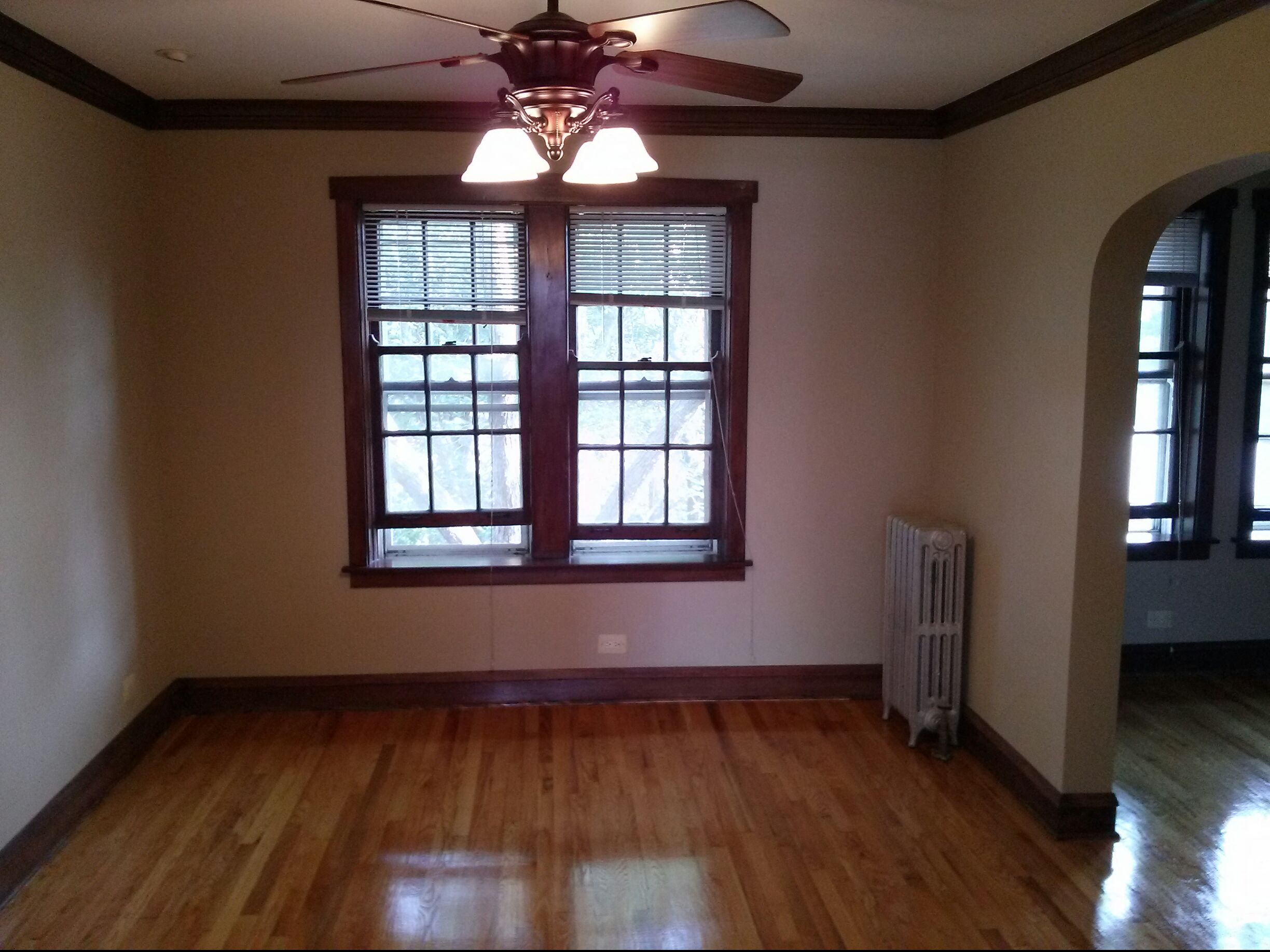 an empty living room with a ceiling fan and windows