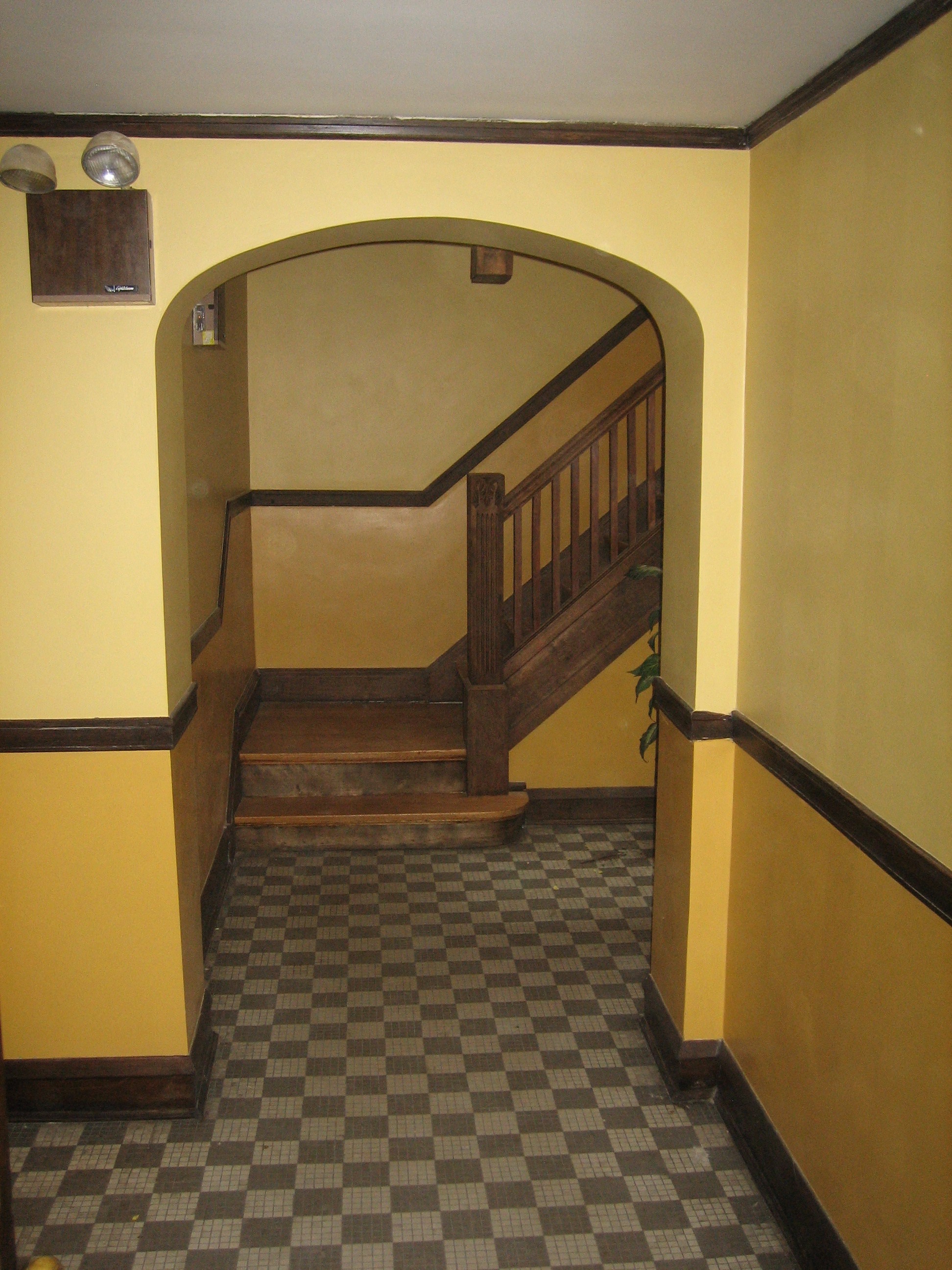 a hallway with a staircase and a checkered floor