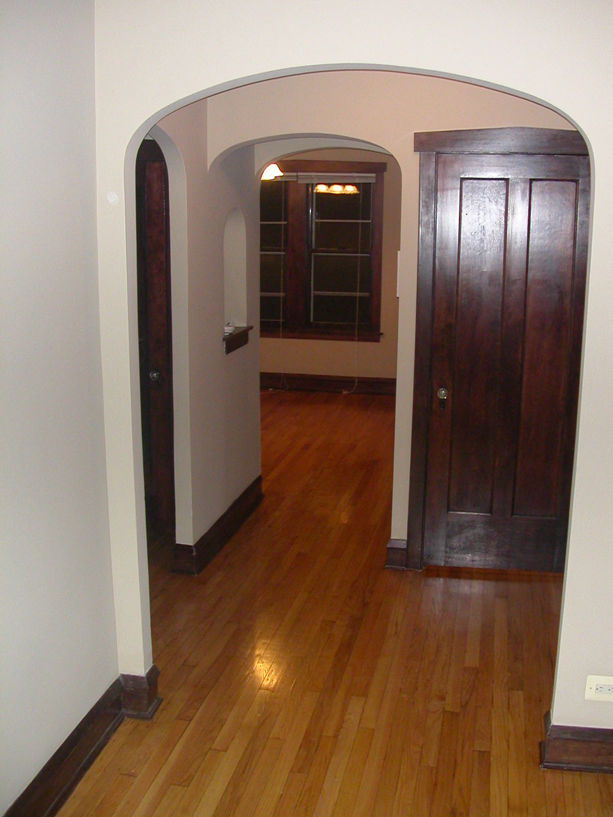 an arched doorway into a living room with wood flooring and a wooden door