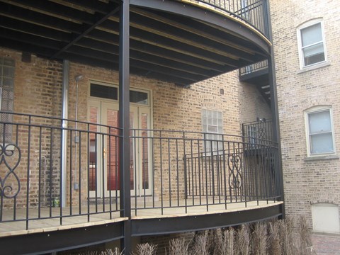 the balcony of a brick apartment building with a wrought iron railing