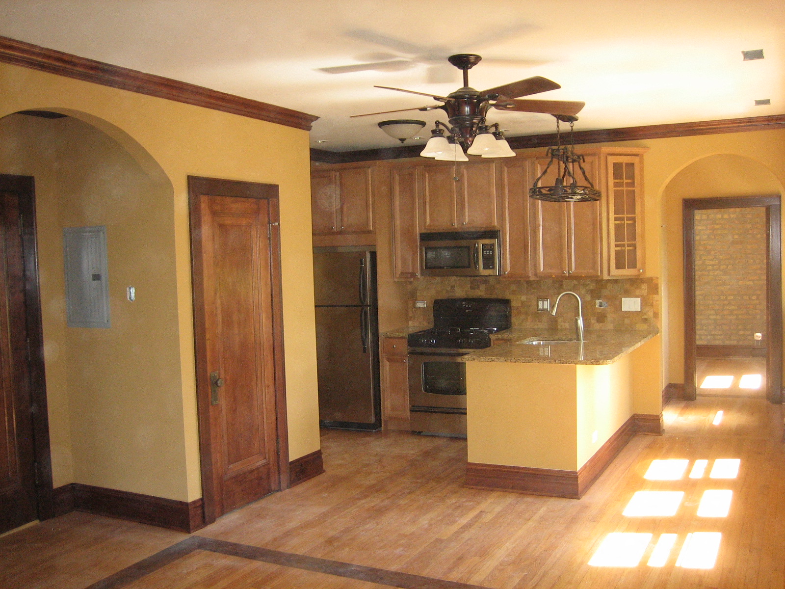 an empty kitchen with a ceiling fan and wooden cabinets