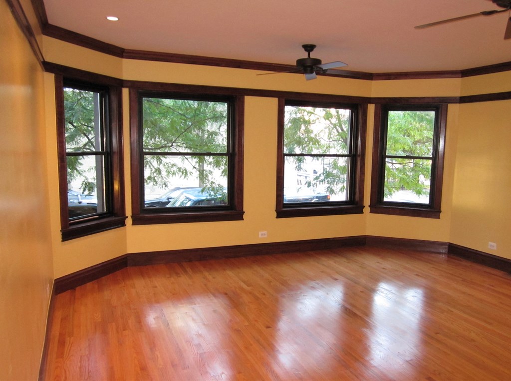 an empty living room with a hard wood floor and large windows