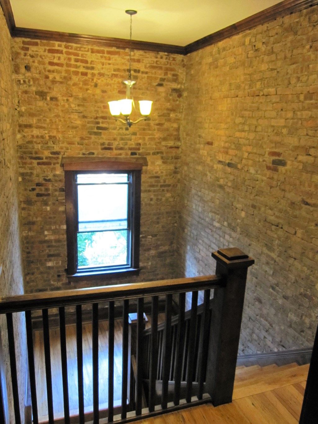 a brick wall with a window and a wooden staircase
