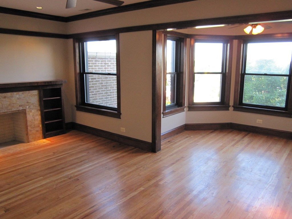 an empty living room with a fireplace and wood floors