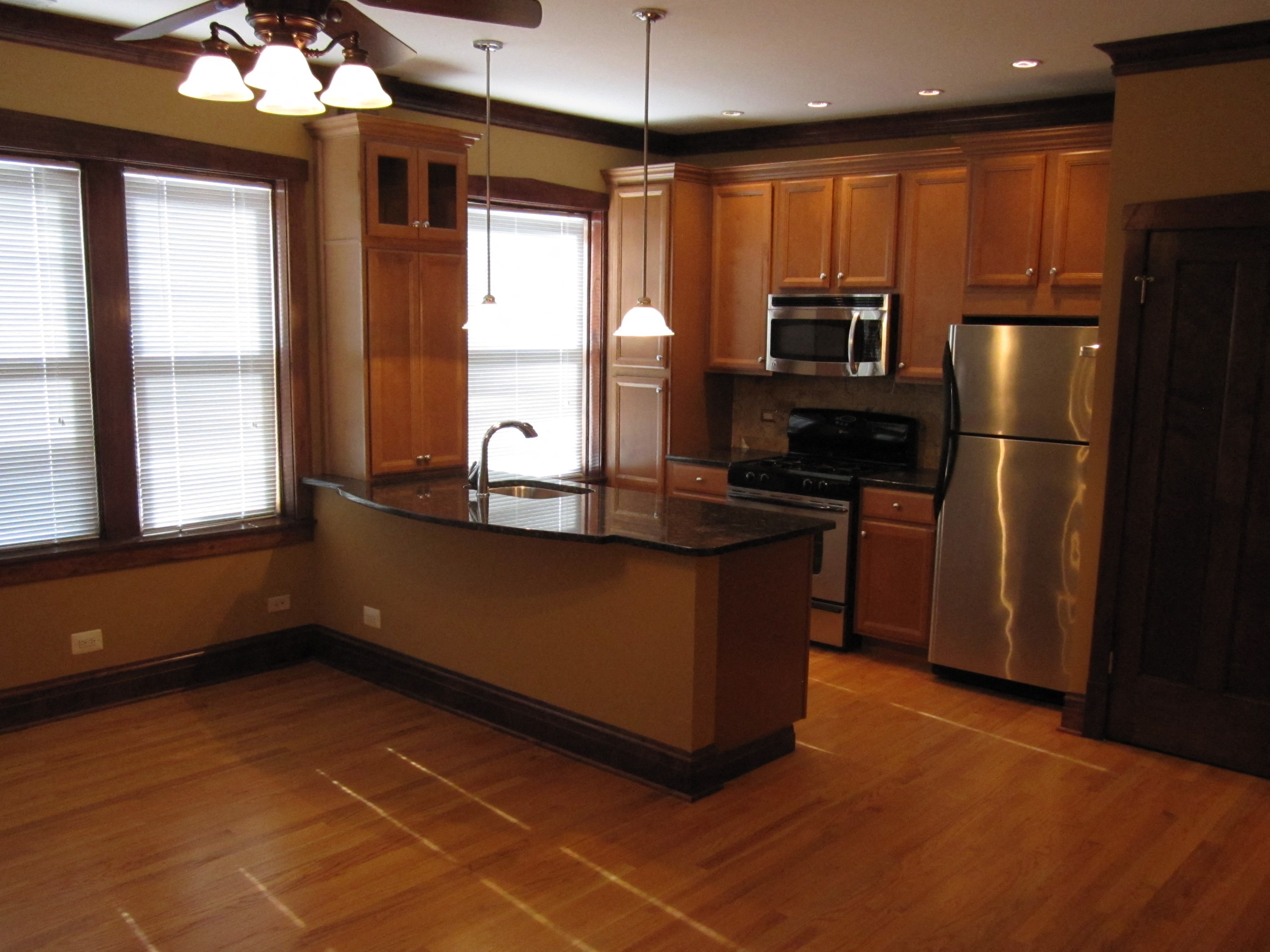 an empty kitchen with wooden floors and stainless steel appliances