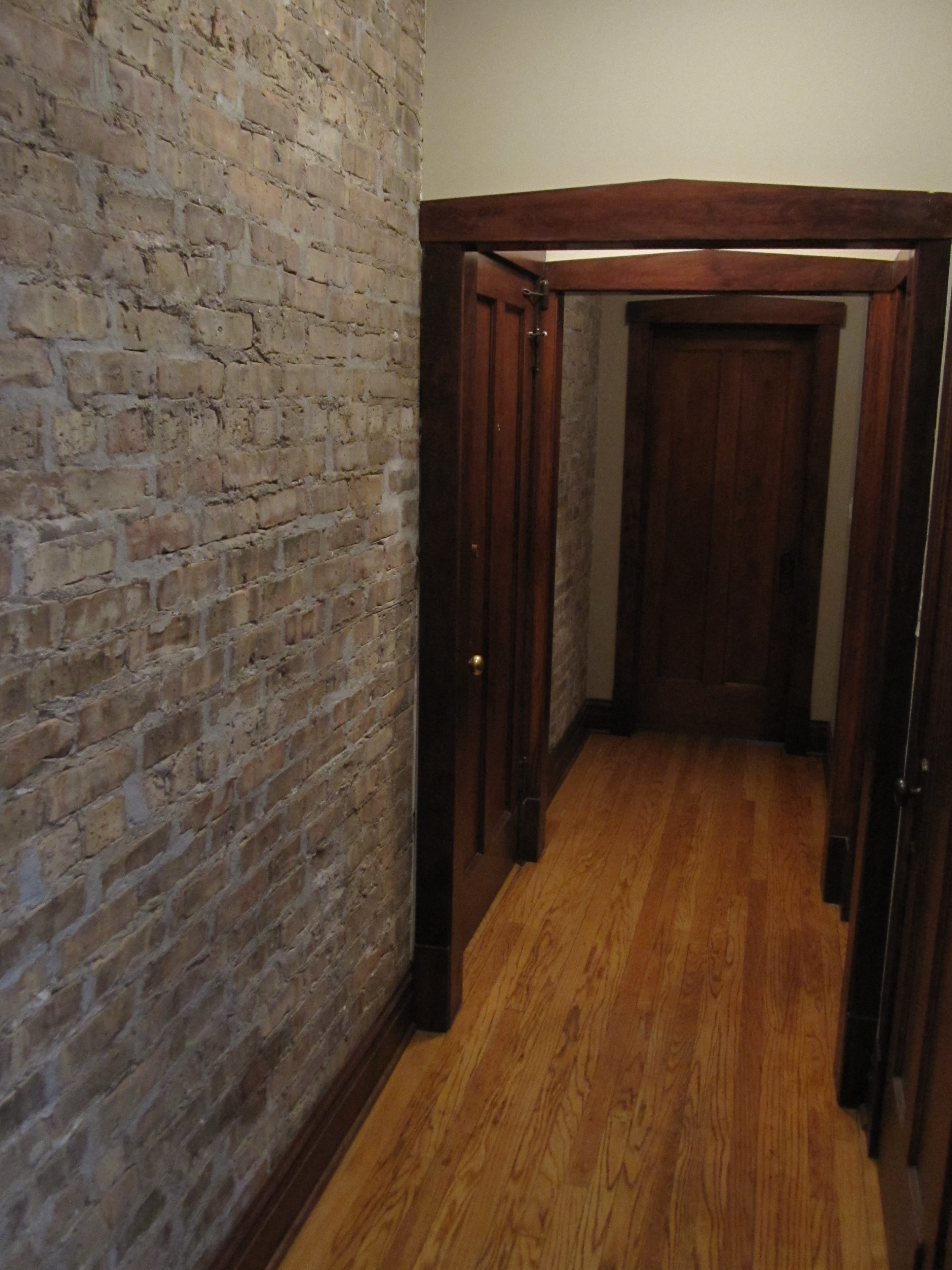 a hallway with a brick wall and wooden floors