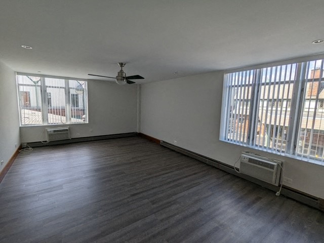 an empty living room with wood floors and a ceiling fan