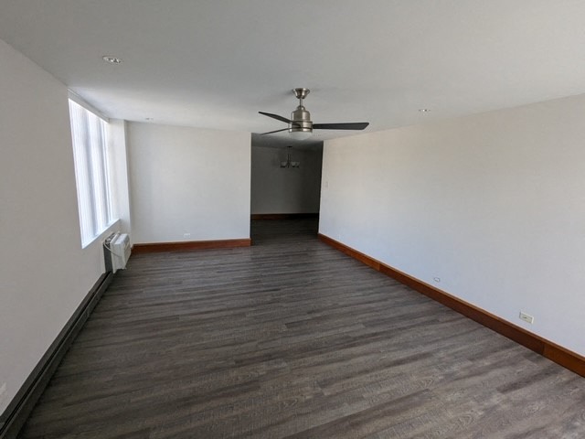 an empty living room with wood floors and a ceiling fan