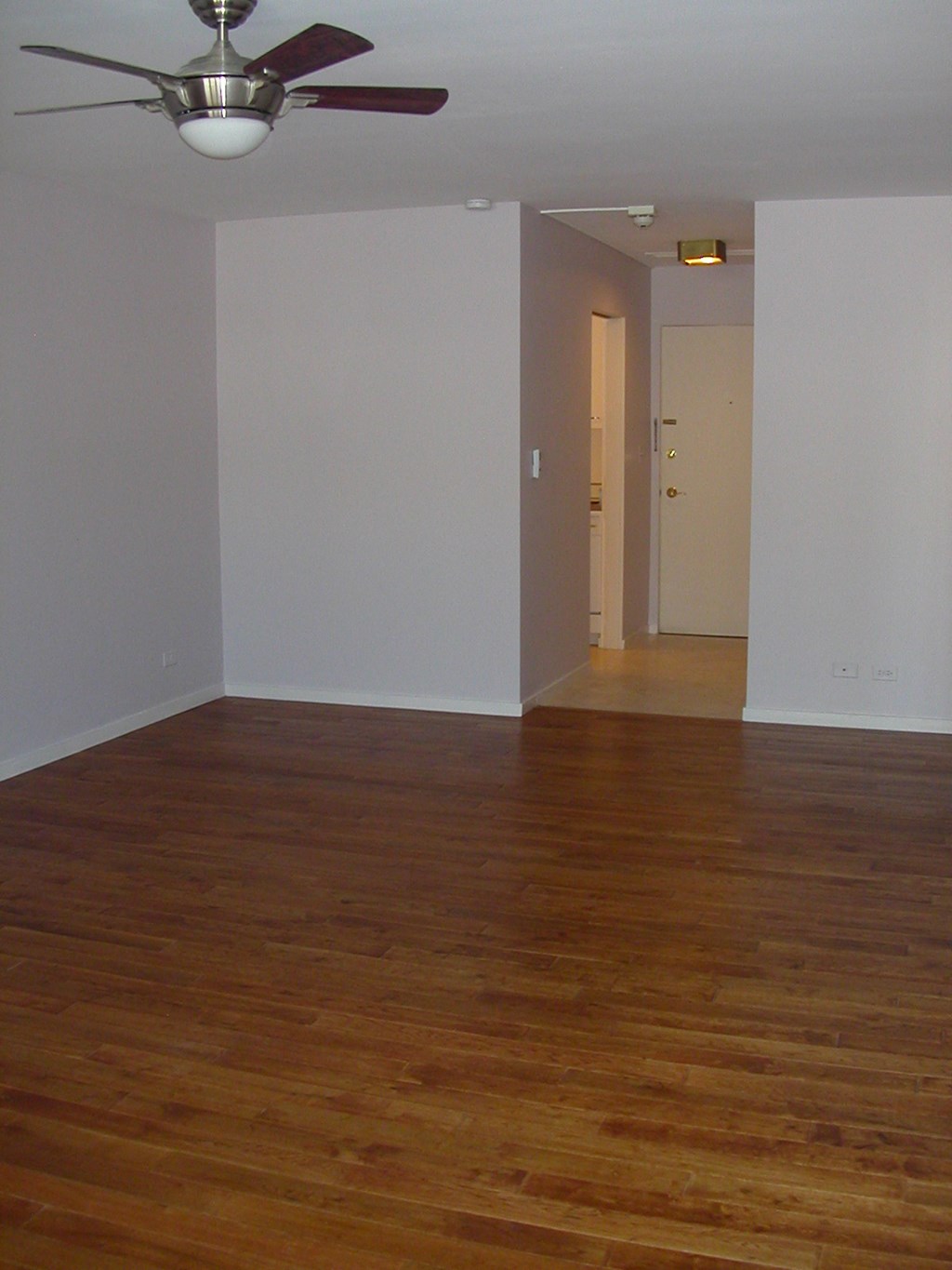 an empty living room with wooden floors and a ceiling fan