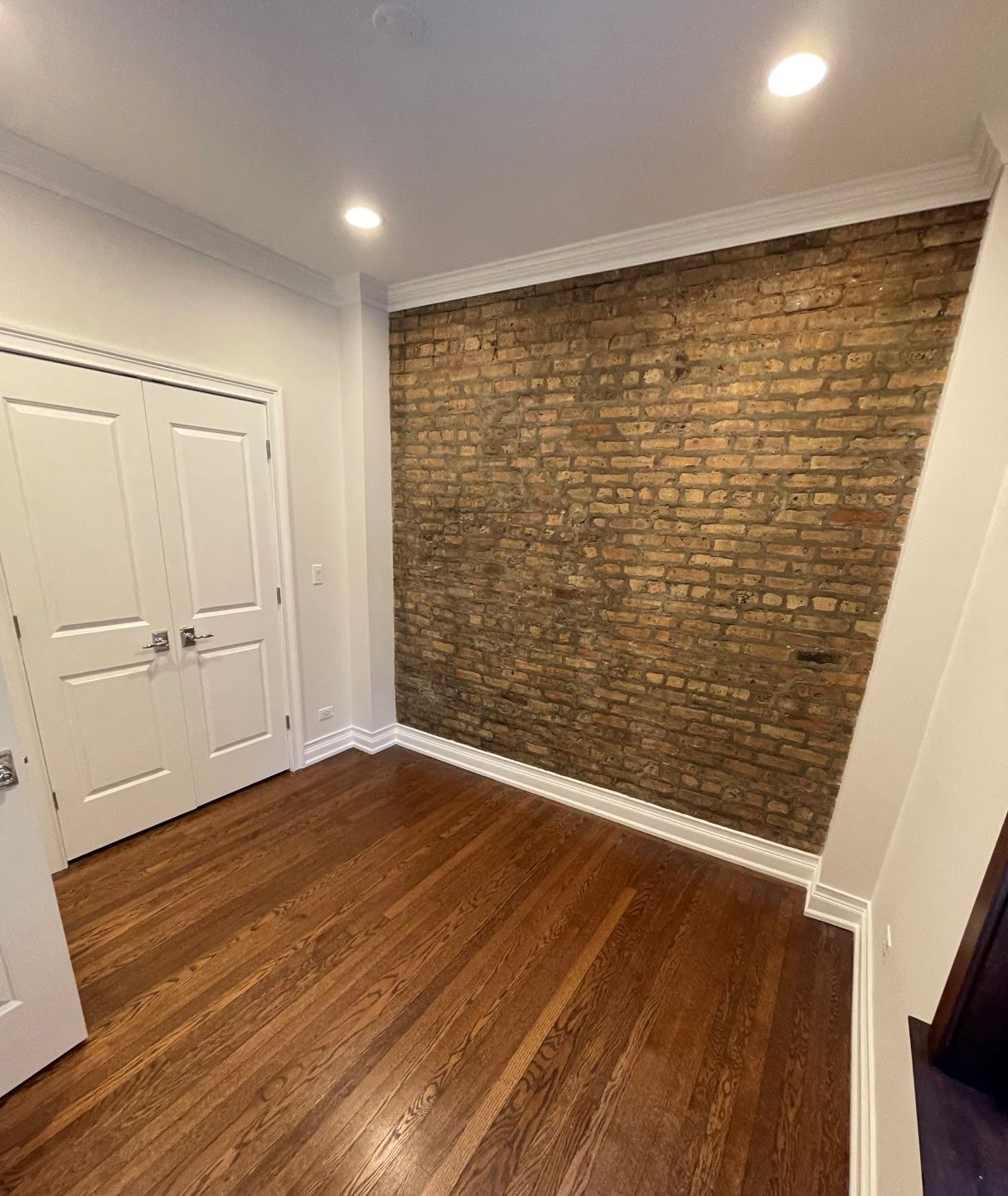 a living room with a brick wall and wooden floors