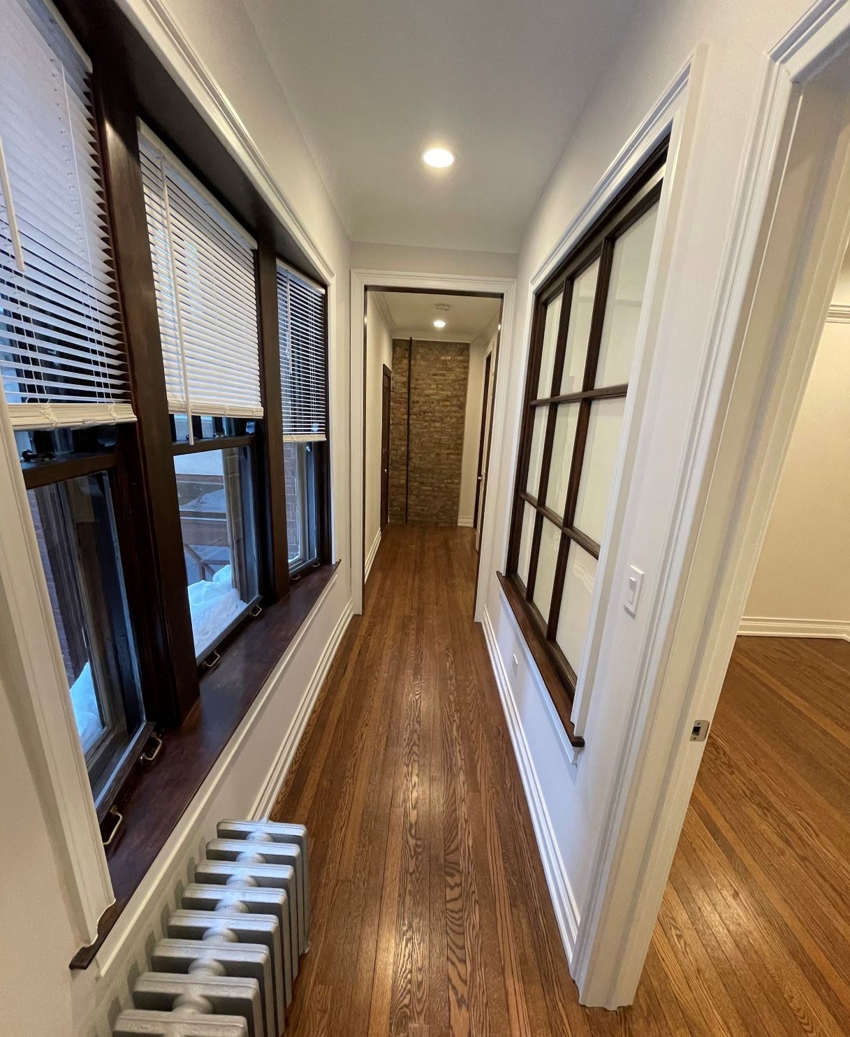 a hallway with windows and a wooden floor and a staircase