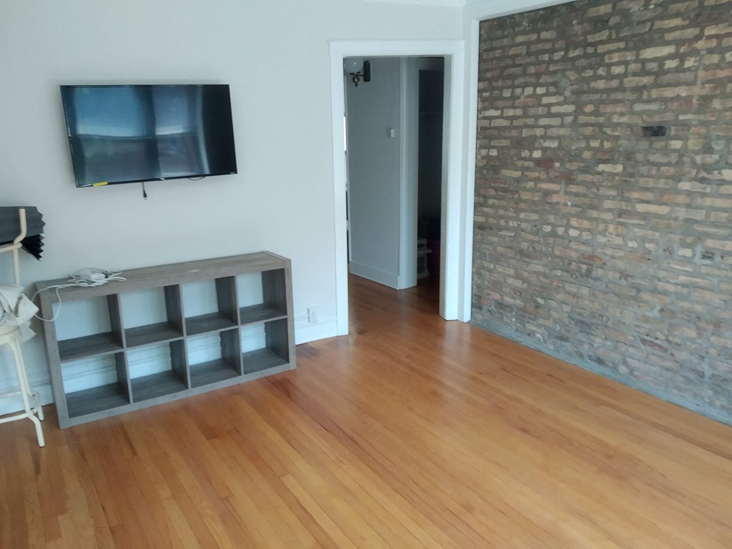 a living room with wooden floors and a tv on the wall