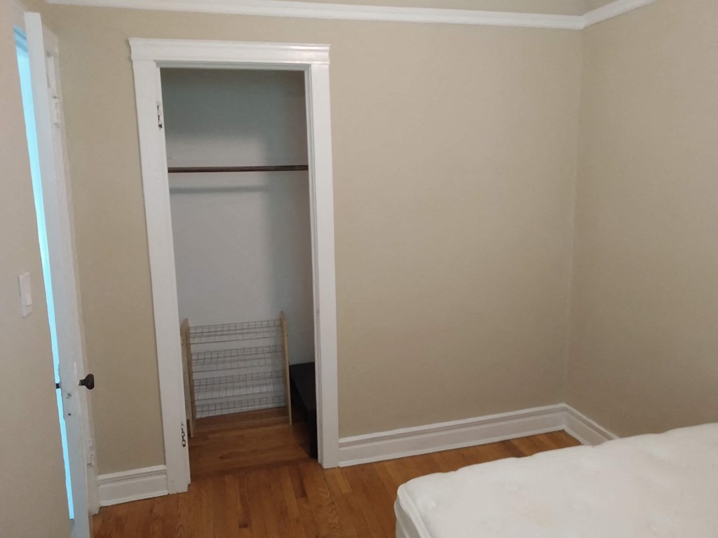 a closet in a bedroom with a bed and a door open