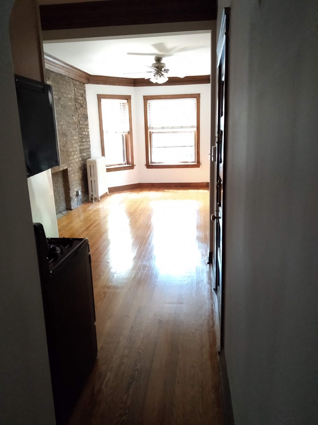 an empty living room with wood floors and a ceiling fan