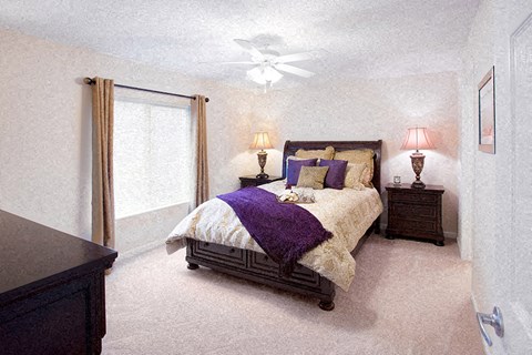 A bedroom with a bed, nightstands, and a ceiling fan.