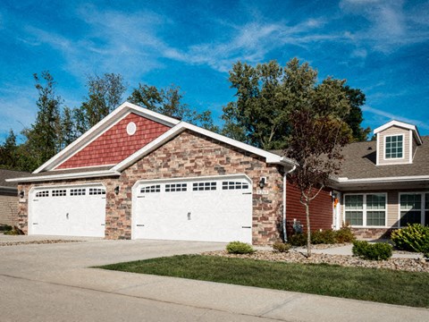 A house with a red roof and two white garage doors.