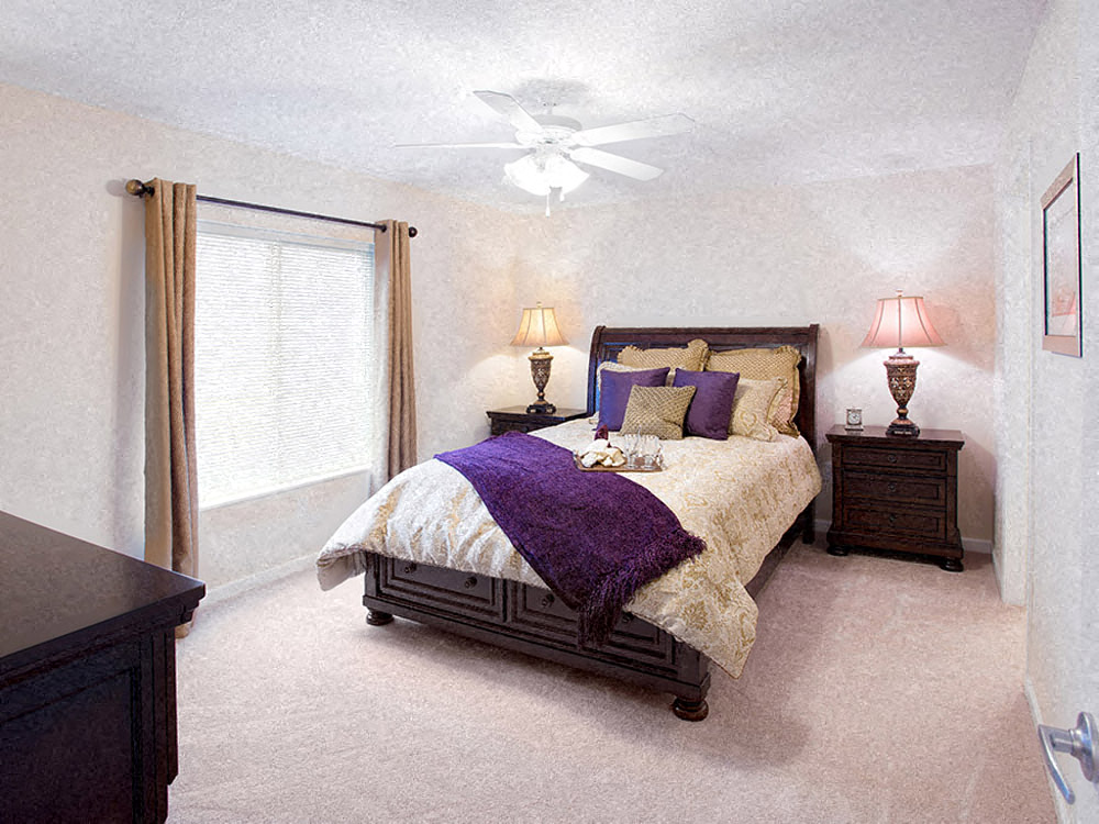 A bedroom with a bed, nightstands, and a ceiling fan.