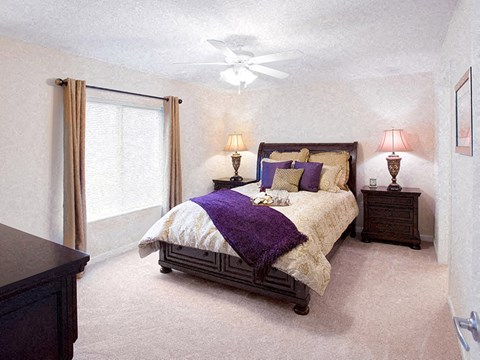 A bedroom with a bed, nightstands, and a ceiling fan.