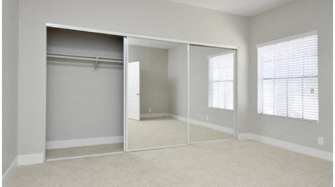 an empty bedroom with a mirrored closet door