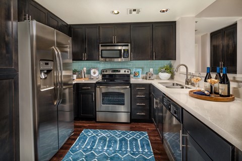 A modern kitchen with dark wood cabinets and stainless steel appliances.