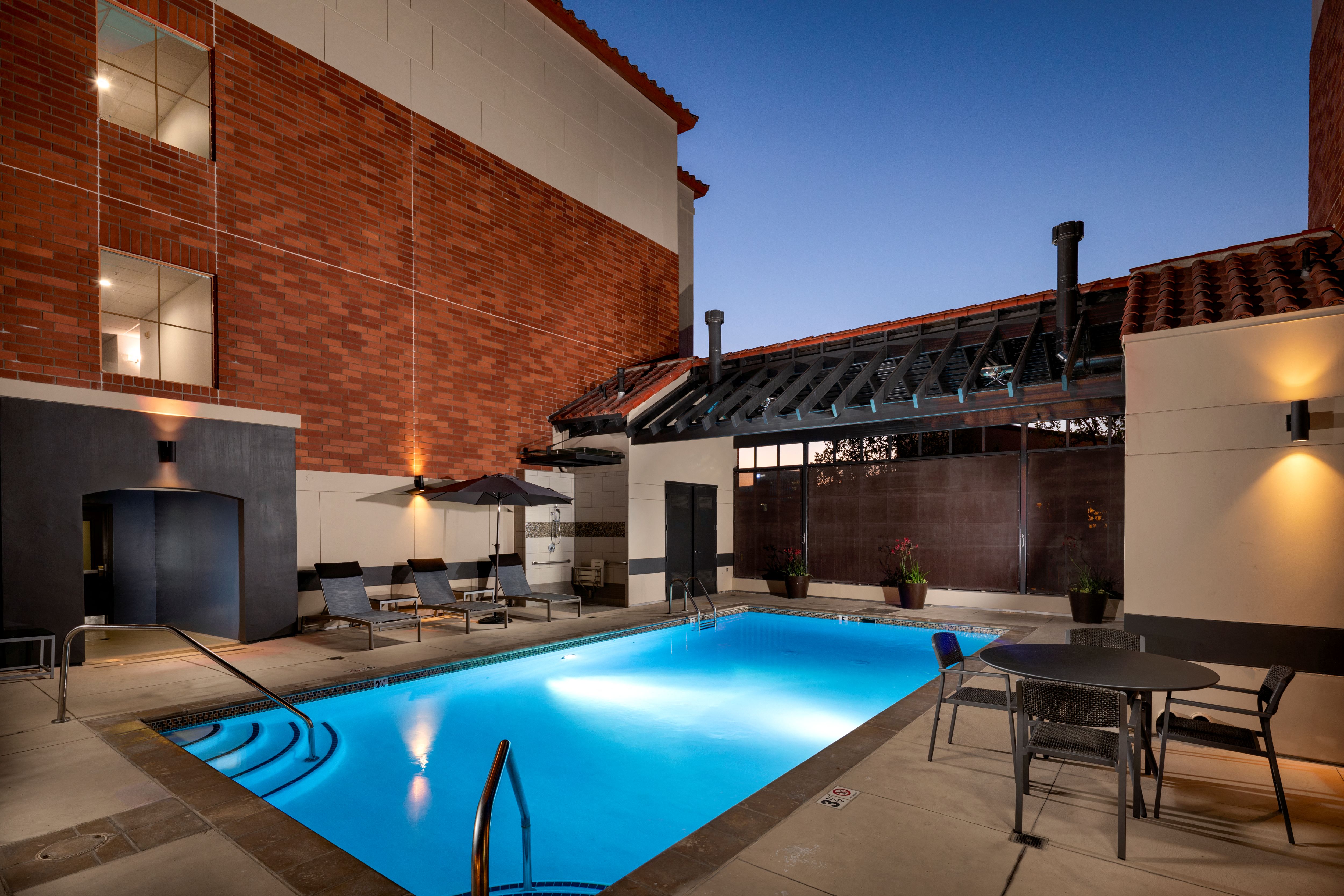 A swimming pool in a backyard with a table and chairs.