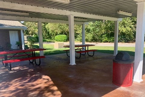 a picnic pavilion with benches and a trash can
