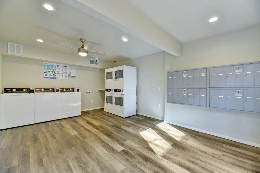 a large room with white appliances and cabinets and wood flooring