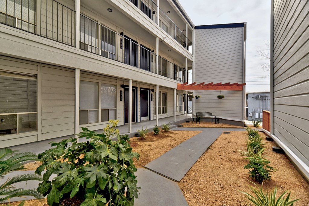 the courtyard of an apartment building with a walkway and a bench
