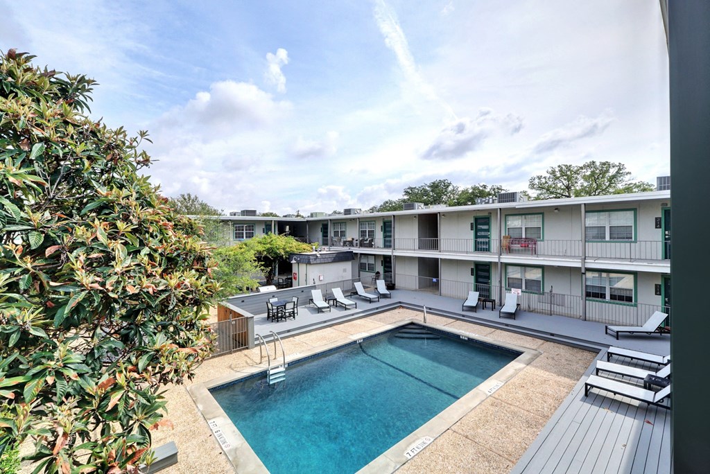 a swimming pool with lounge chairs in front of an apartment building