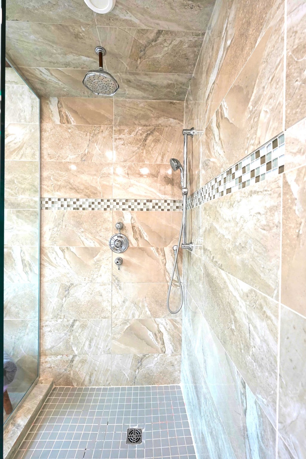 a large shower with two showerheads in a marble bathroom