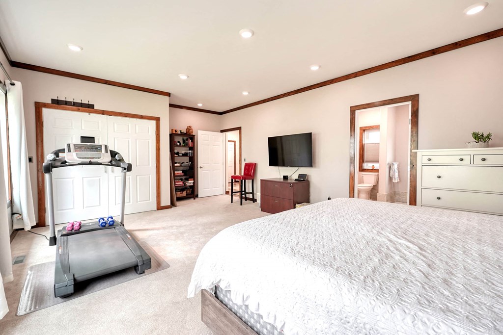 the master bedroom has a large bed and a large closet with a tv